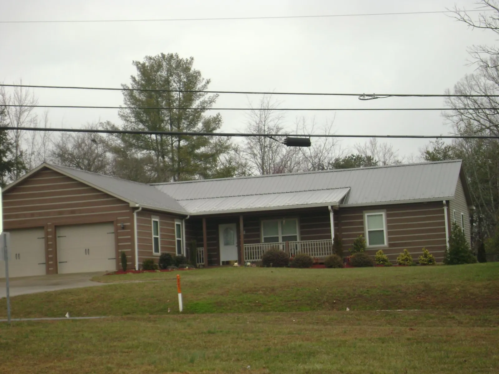Gray metal roof on a log sided ranch home with a front porch in Bluffton