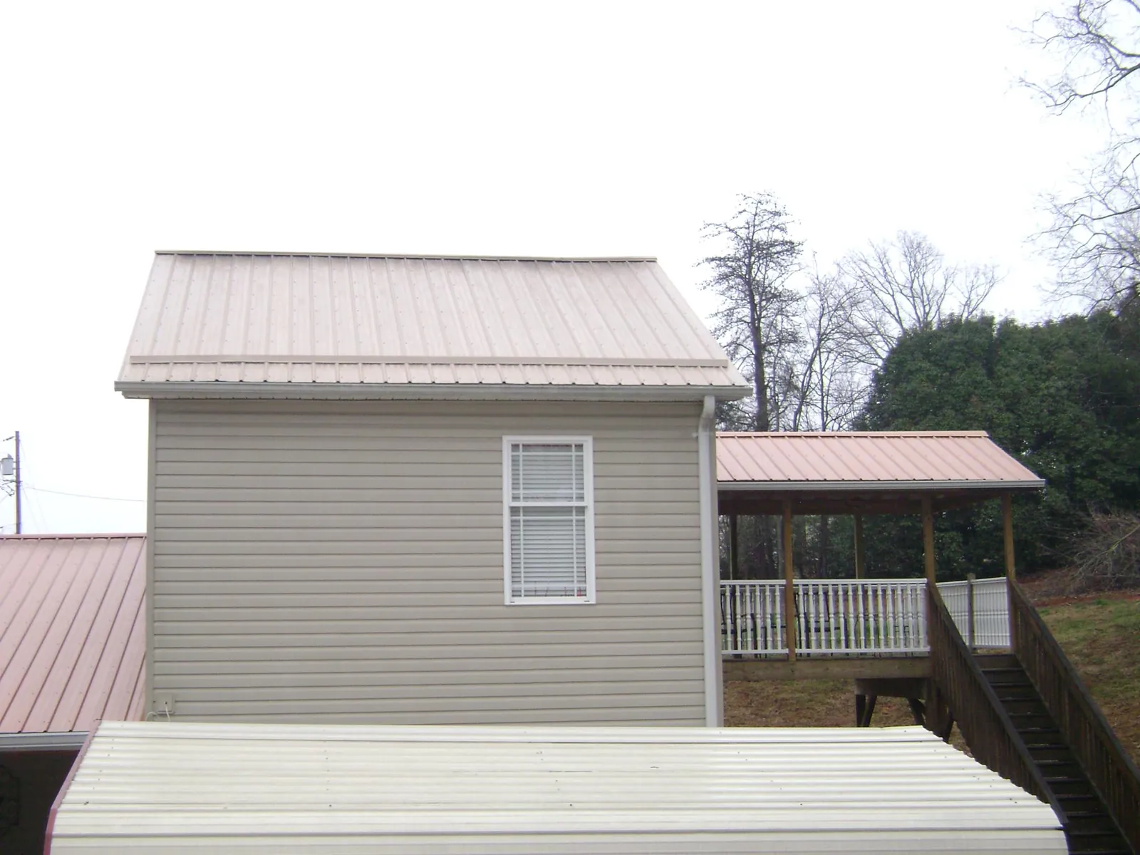Tan metal roofs on a two story addition and attached porch, from a Roof Replacement job in Bluffton
